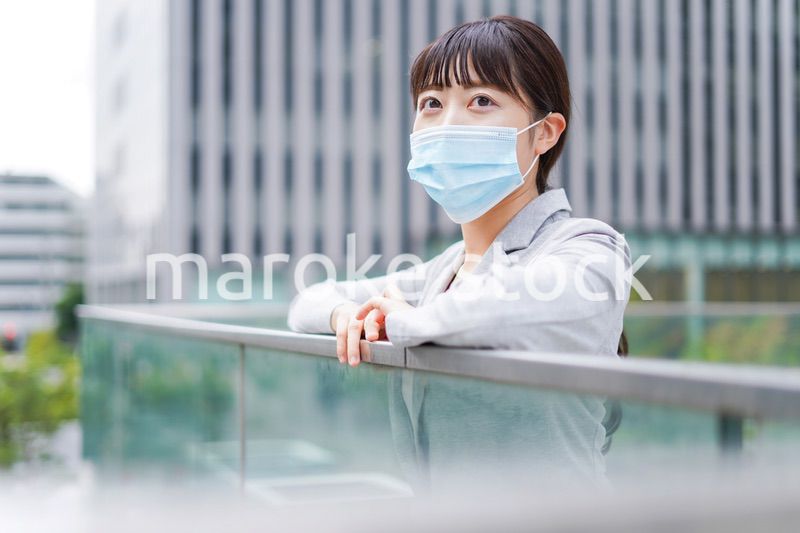 マスクをして外で休憩をする若いビジネスウーマン