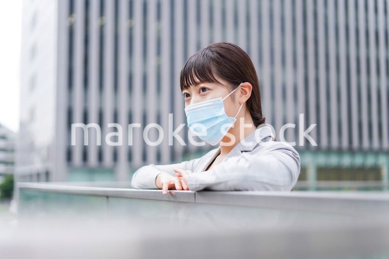 マスクをして外で休憩をする若いビジネスウーマン
