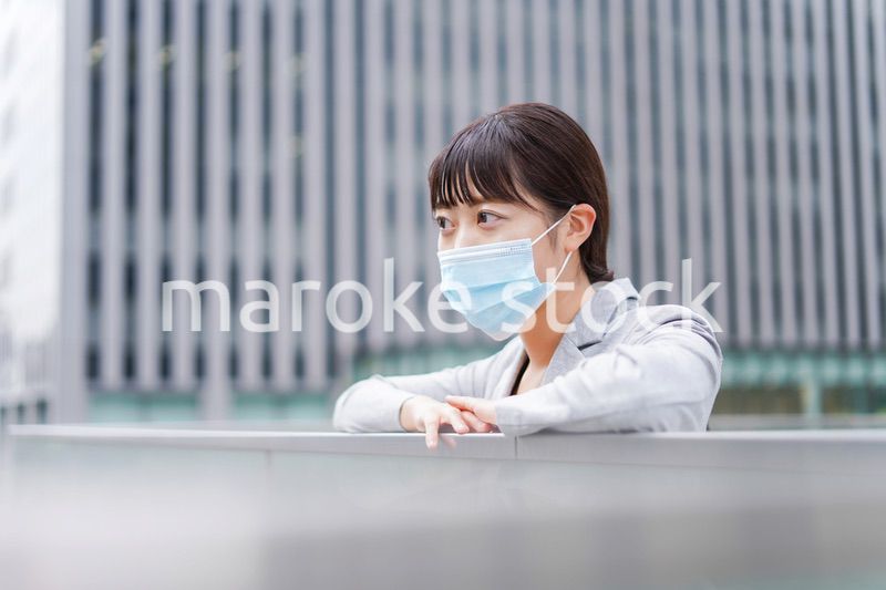 マスクをして外で休憩をする若いビジネスウーマン