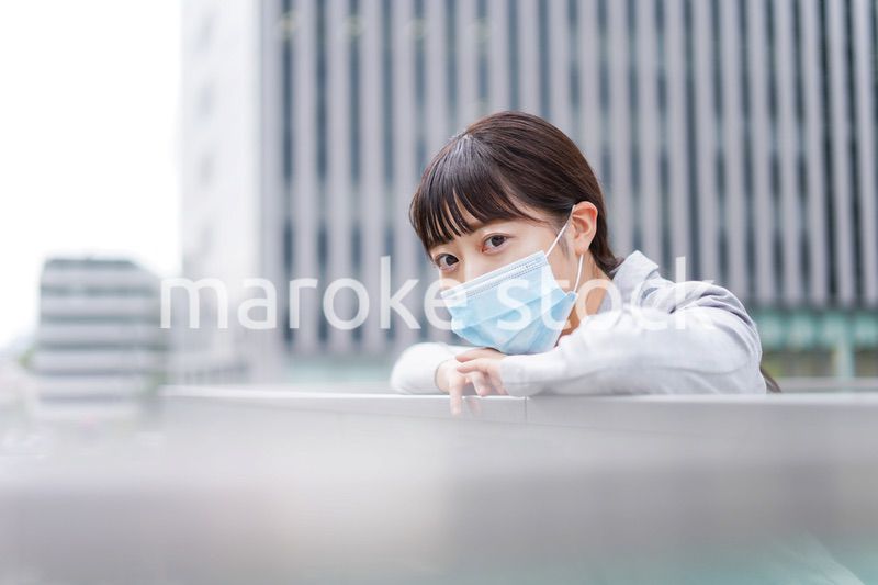 マスクをして外で休憩をする若いビジネスウーマン