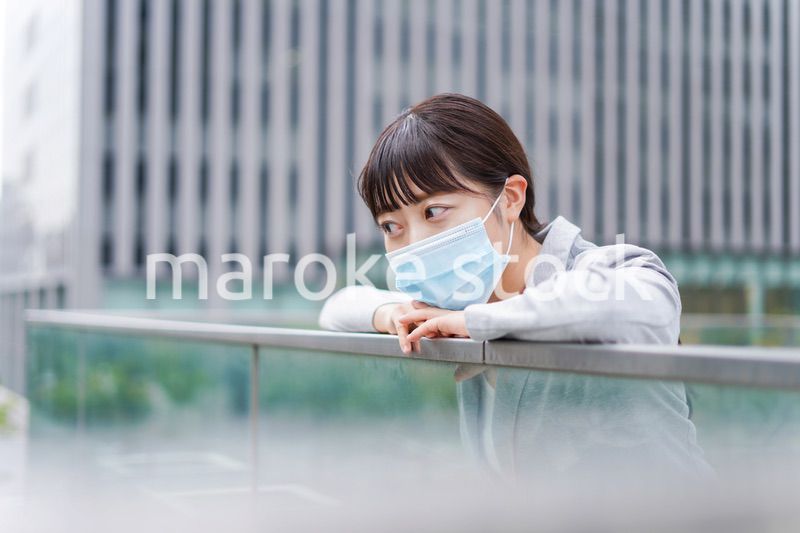 マスクをして外で休憩をする若いビジネスウーマン