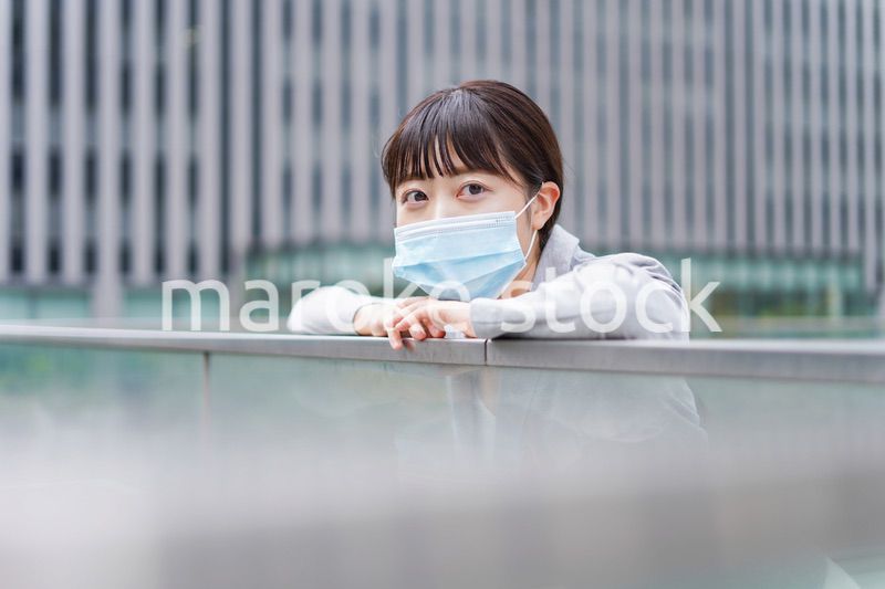 マスクをして外で休憩をする若いビジネスウーマン