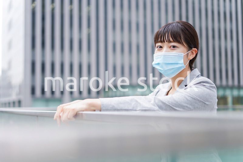 マスクをして外で休憩をする若いビジネスウーマン
