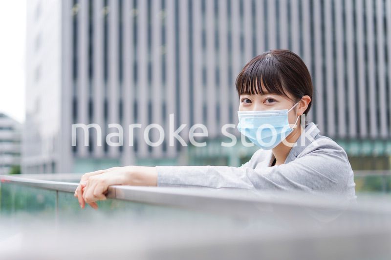 マスクをして外で休憩をする若いビジネスウーマン