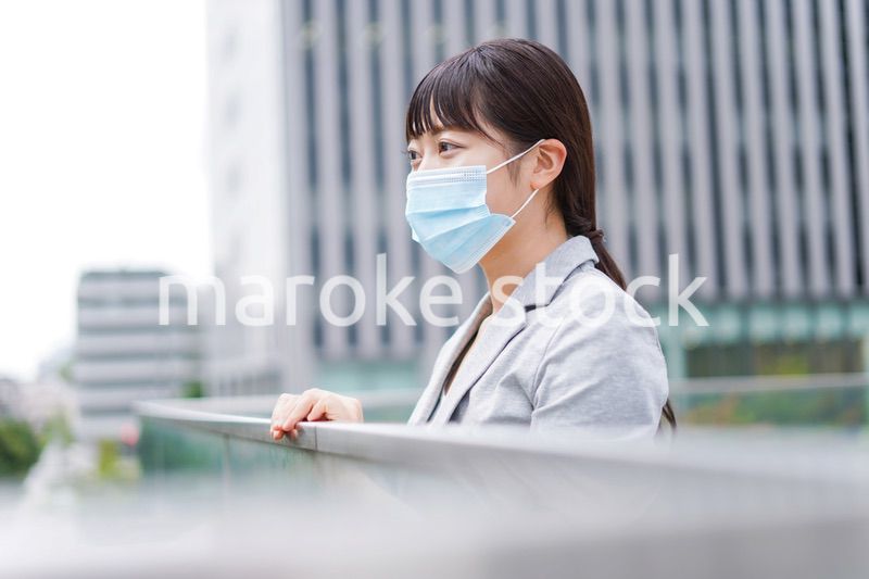マスクをして外で休憩をする若いビジネスウーマン