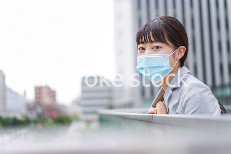 マスクをして外で休憩をする若いビジネスウーマン