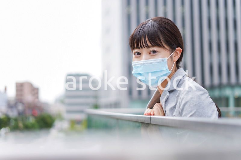 マスクをして外で休憩をする若いビジネスウーマン