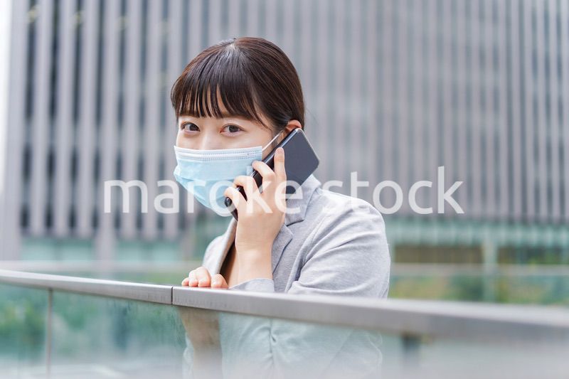 マスクをして電話をする若いビジネスウーマン