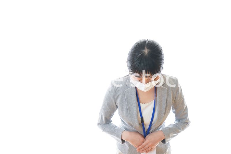 マスクをしてお辞儀をする若いビジネスパーソン