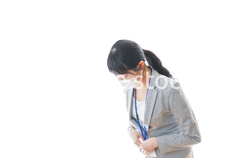 マスクをしてお辞儀をする若いビジネスパーソン