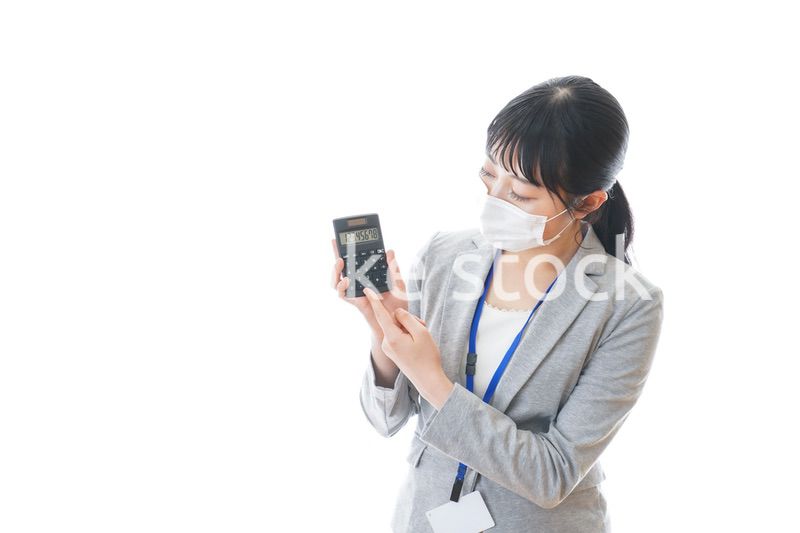 マスクをして電卓を持つ若いビジネスパーソン