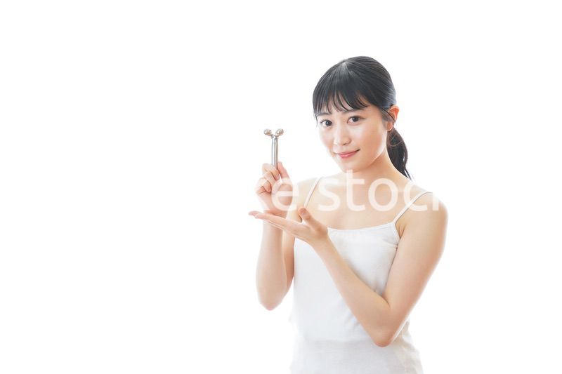 かっさで肌をマッサージをする若い女性