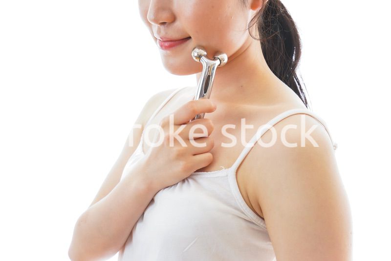 かっさで肌をマッサージをする若い女性