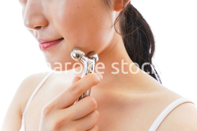 かっさで肌をマッサージをする若い女性