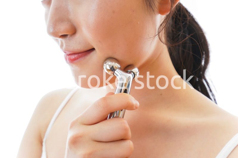 かっさで肌をマッサージをする若い女性