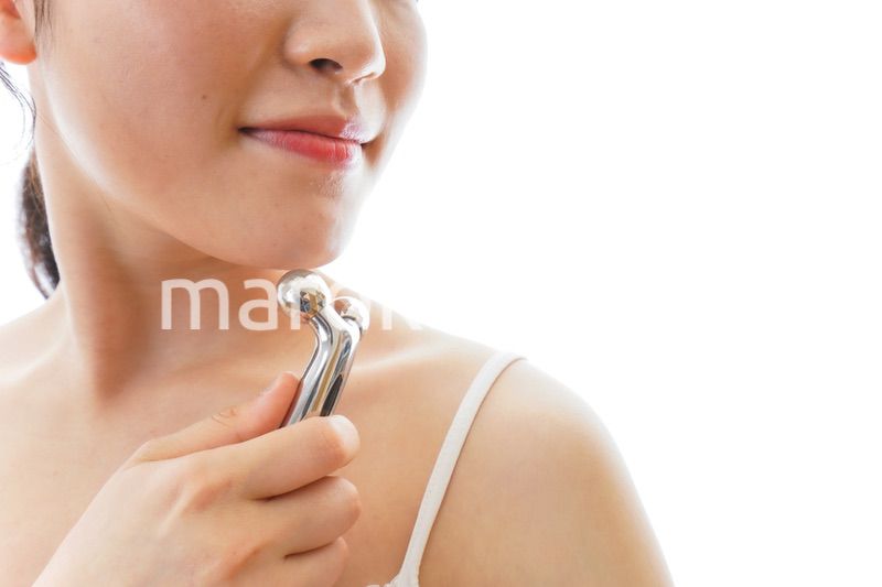 かっさで肌をマッサージをする若い女性