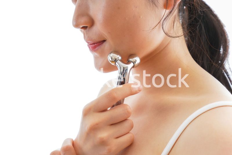 かっさで肌をマッサージをする若い女性