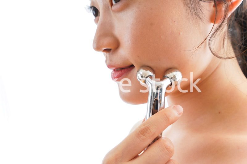 かっさで肌をマッサージをする若い女性