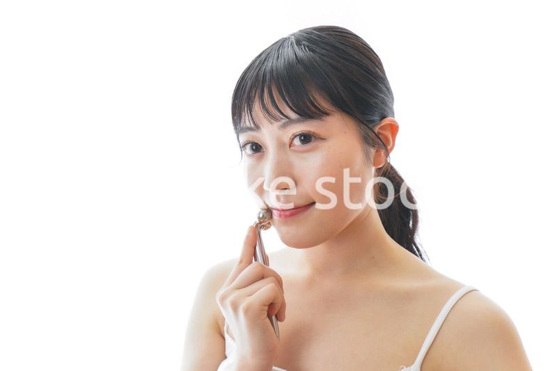 かっさで肌をマッサージをする若い女性