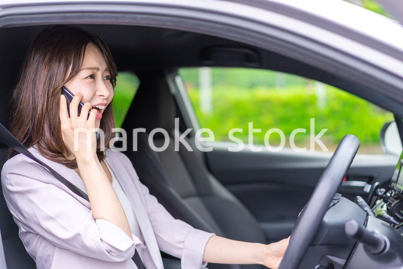 スマホを使いながら車を運転する女性