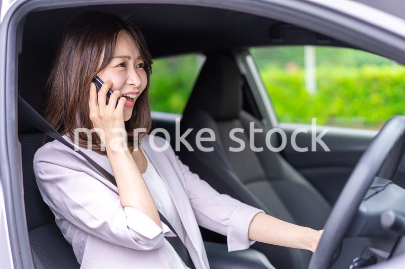 スマホを使いながら車を運転する女性
