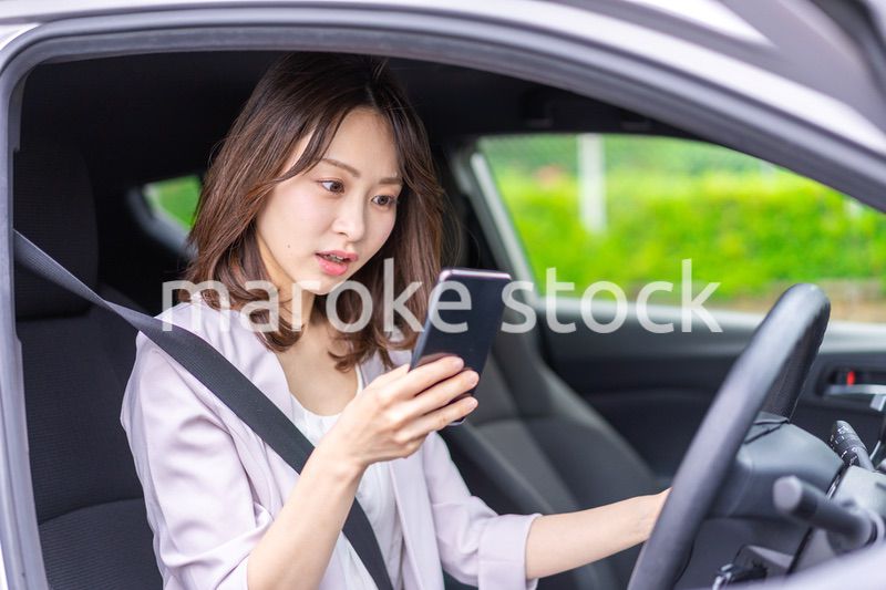 スマホを使いながら車を運転する女性