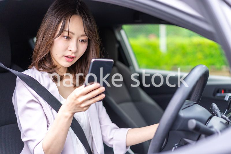 スマホを使いながら車を運転する女性