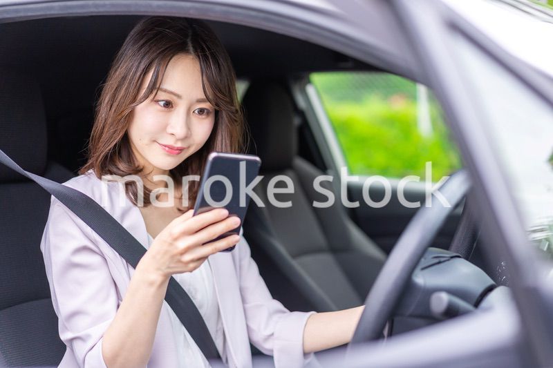 スマホを使いながら車を運転する女性