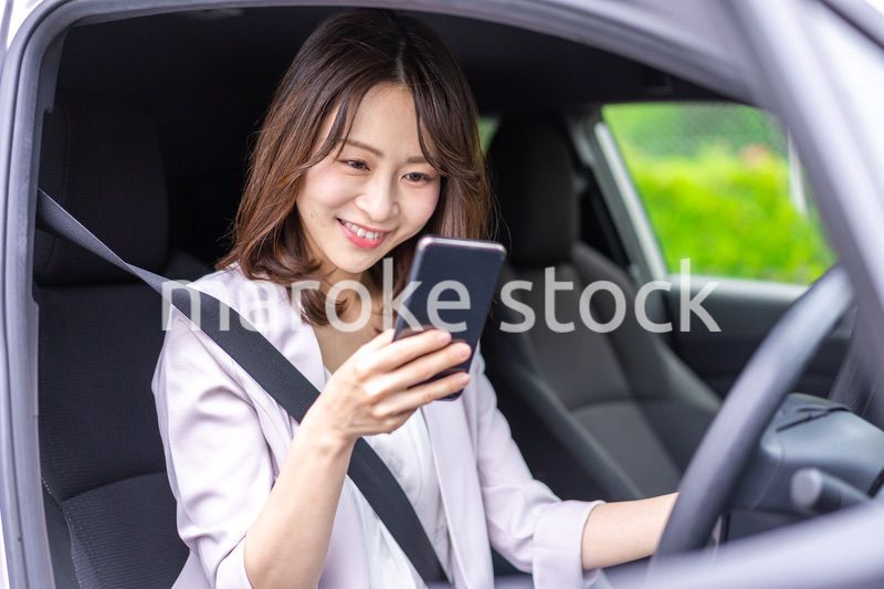 スマホを使いながら車を運転する女性