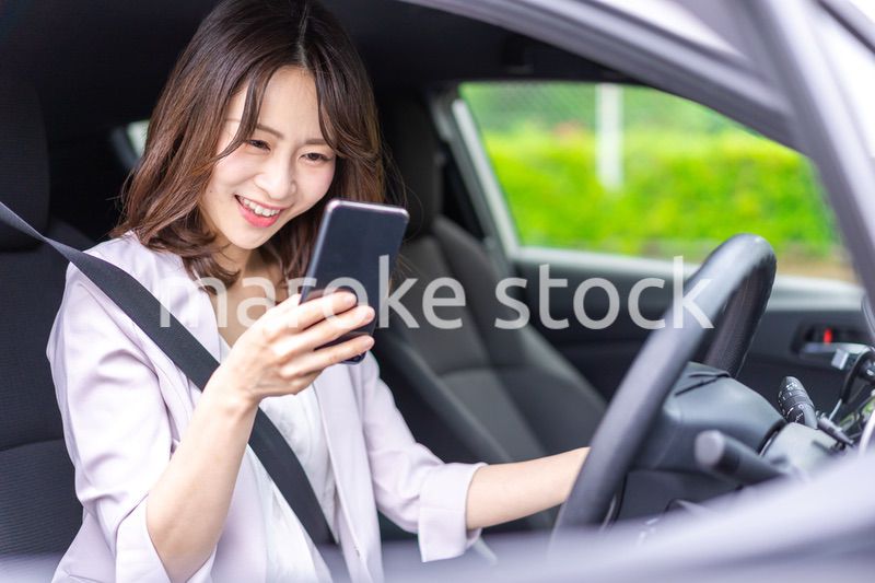 スマホを使いながら車を運転する女性