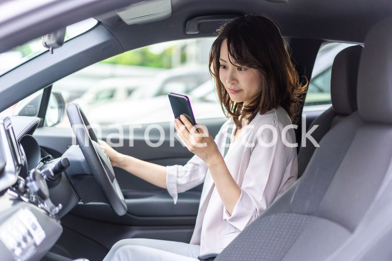 スマホを使いながら車を運転する女性