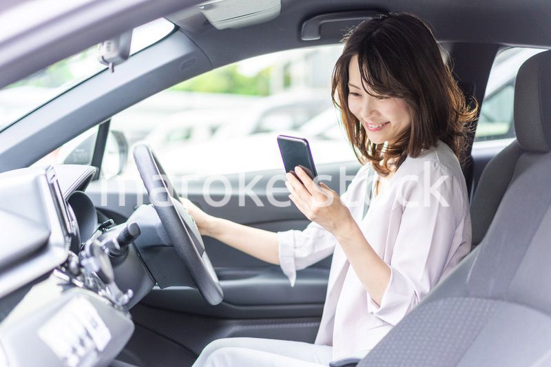 スマホを使いながら車を運転する女性