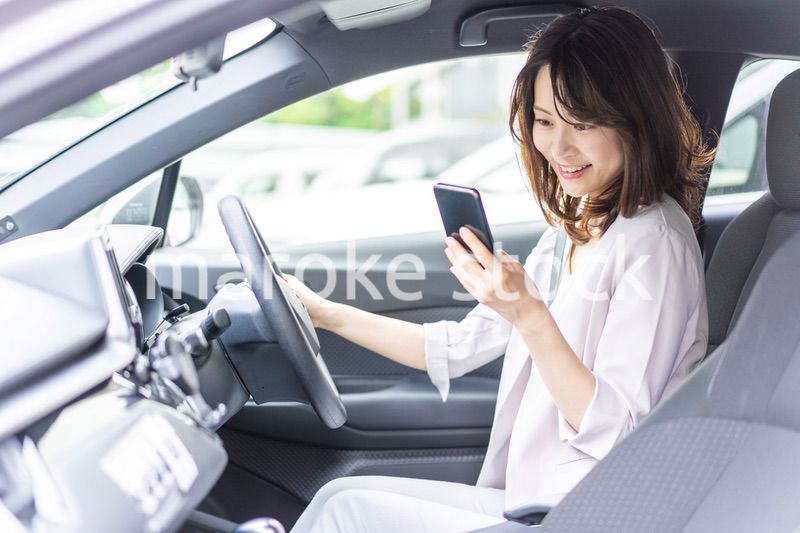 スマホを使いながら車を運転する女性