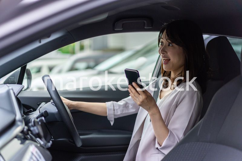 スマホを使いながら車を運転する女性