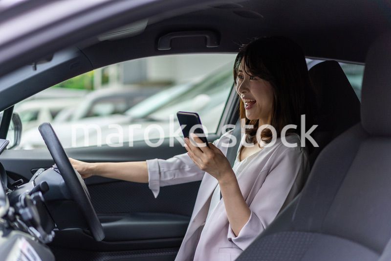 スマホを使いながら車を運転する女性