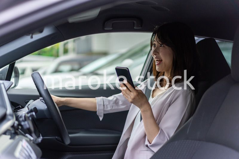 スマホを使いながら車を運転する女性