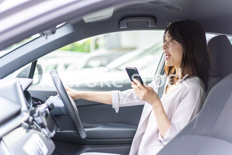 スマホを使いながら車を運転する女性