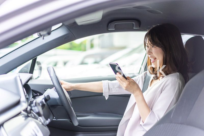 スマホを使いながら車を運転する女性