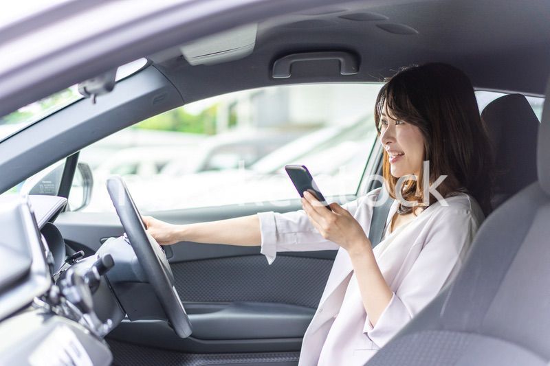 スマホを使いながら車を運転する女性