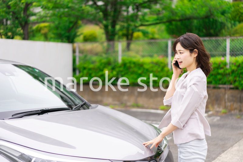 車が故障して連絡をする若い女性