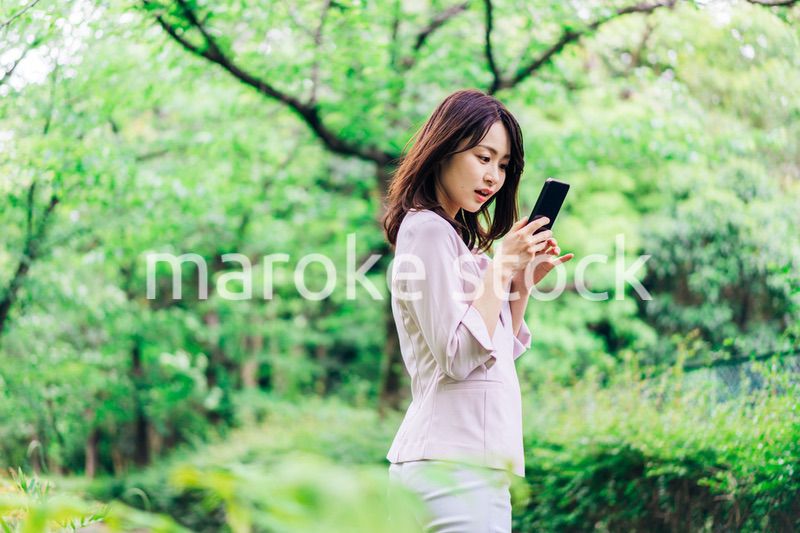 外でスマホを使うビジネスウーマン
