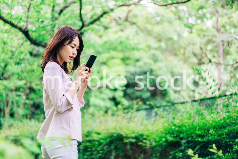 外でスマホを使うビジネスウーマン