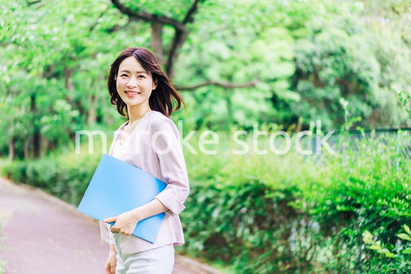 書類を持って歩く若いビジネスウーマン