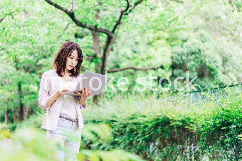 外でパソコンを使う若いビジネスウーマン