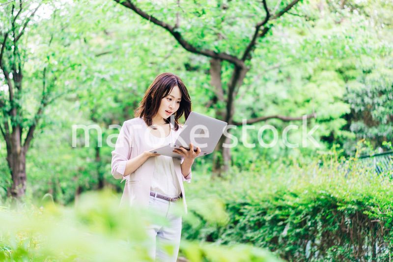 外でパソコンを使う若いビジネスウーマン