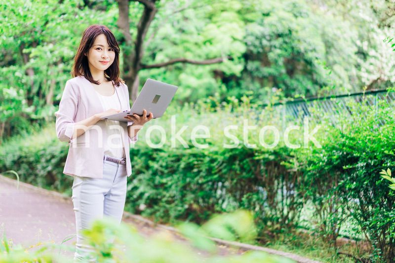 外でパソコンを使う若いビジネスウーマン