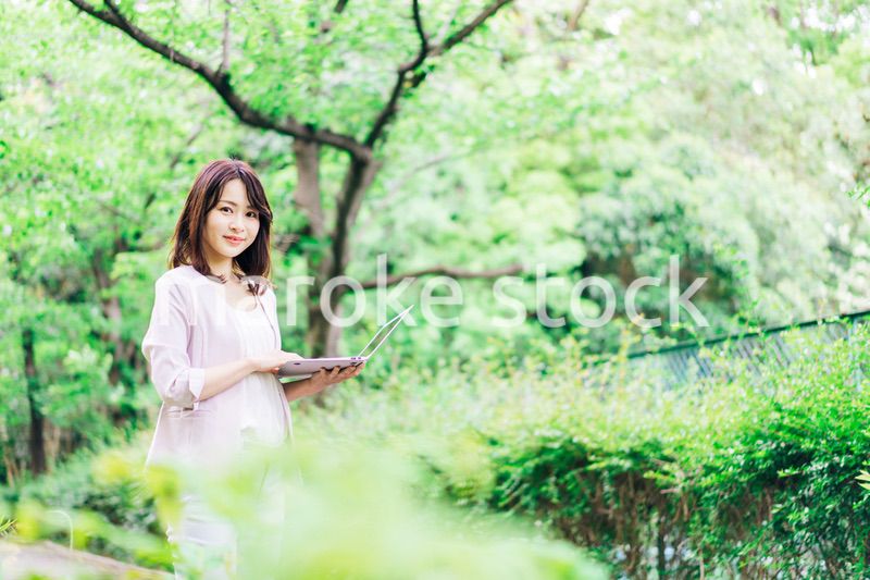 外でパソコンを使う若いビジネスウーマン