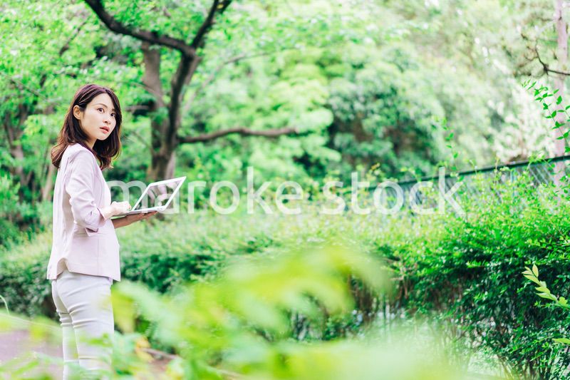 外でパソコンを使う若いビジネスウーマン