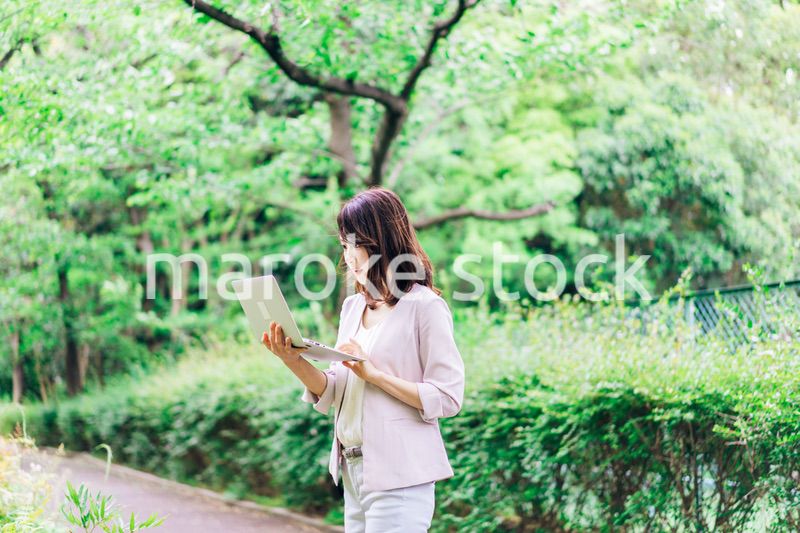 外でパソコンを使う若いビジネスウーマン