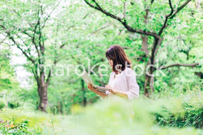 外でパソコンを使う若いビジネスウーマン